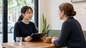 海外のカフェで英語による仕事の面接を受ける日本人女性